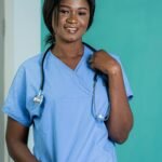 African nurse in blue scrubs smiling, representing healthcare professionals.